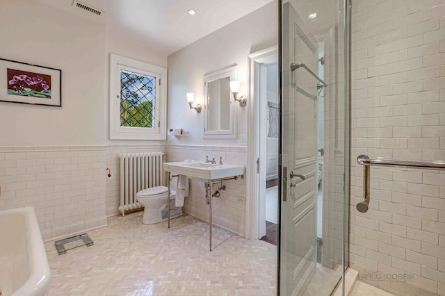 full bathroom with radiator, sink, separate shower and tub, toilet, and tile walls