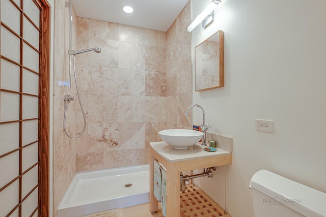 bathroom with toilet, sink, and a tile shower