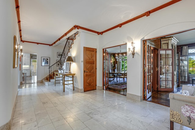 foyer with ornamental molding and a chandelier