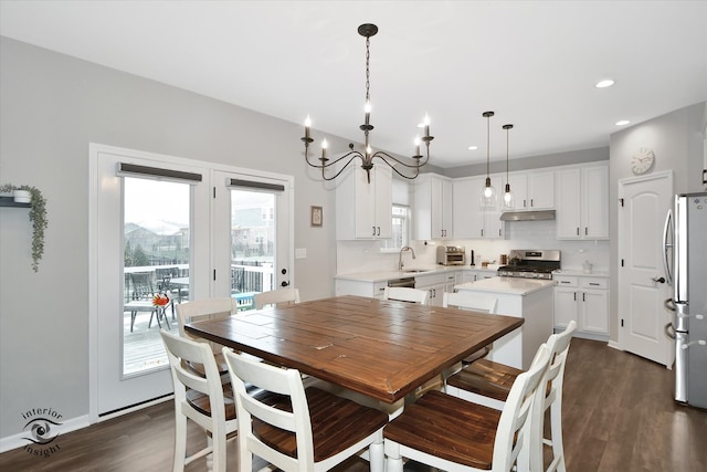 dining space with dark hardwood / wood-style floors, a notable chandelier, and sink