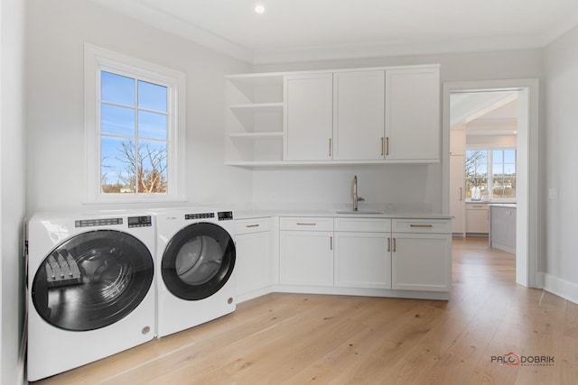 clothes washing area with sink, crown molding, cabinets, separate washer and dryer, and light wood-type flooring