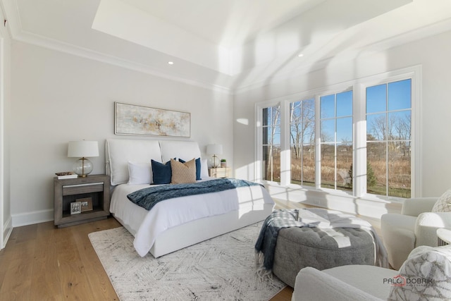 bedroom with crown molding, hardwood / wood-style flooring, and a raised ceiling