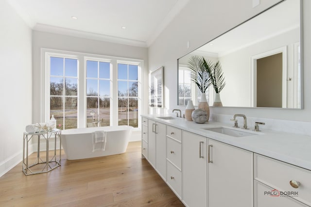 bathroom featuring crown molding, vanity, hardwood / wood-style floors, and a bathtub