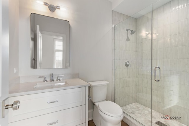 bathroom featuring a shower with door, vanity, and toilet