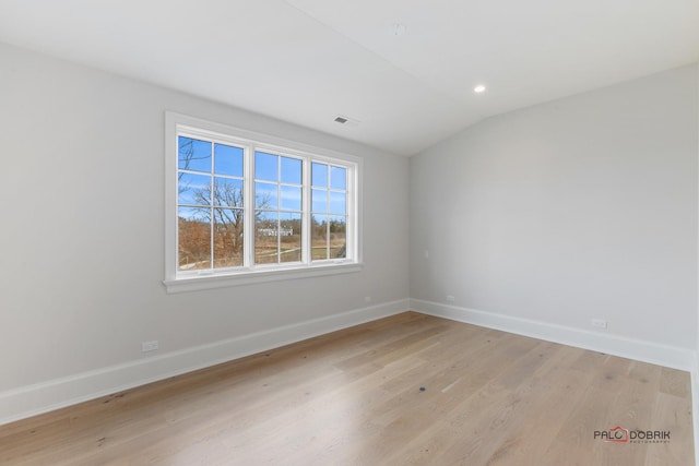 unfurnished room with vaulted ceiling and light hardwood / wood-style flooring