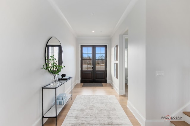 foyer featuring french doors, crown molding, and light hardwood / wood-style flooring