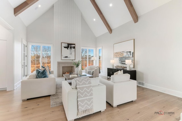 living room featuring light hardwood / wood-style flooring, high vaulted ceiling, a large fireplace, and beamed ceiling