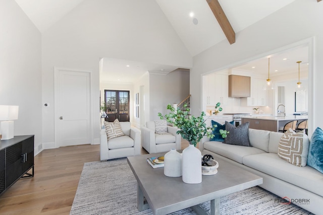 living room with beam ceiling, high vaulted ceiling, and light hardwood / wood-style flooring