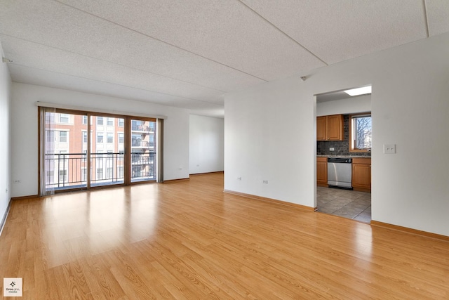 unfurnished living room with a textured ceiling and light hardwood / wood-style flooring