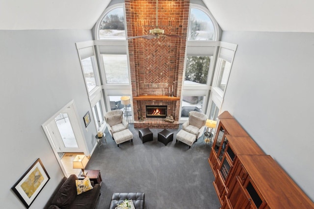 living room featuring a fireplace, high vaulted ceiling, a healthy amount of sunlight, and dark colored carpet