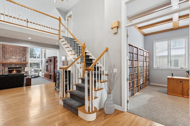 stairway with wood-type flooring, a fireplace, a healthy amount of sunlight, and a high ceiling