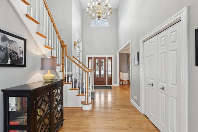 foyer with an inviting chandelier, light hardwood / wood-style floors, and a high ceiling