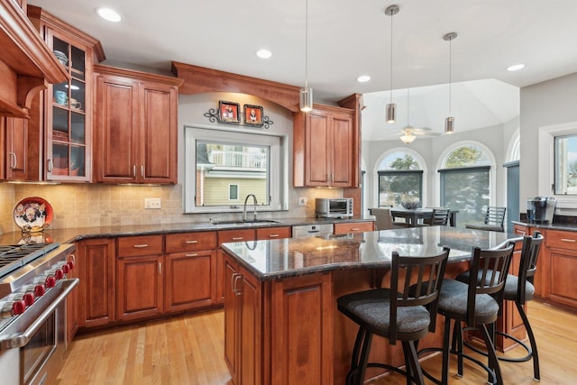 kitchen with pendant lighting, sink, appliances with stainless steel finishes, a center island, and dark stone counters