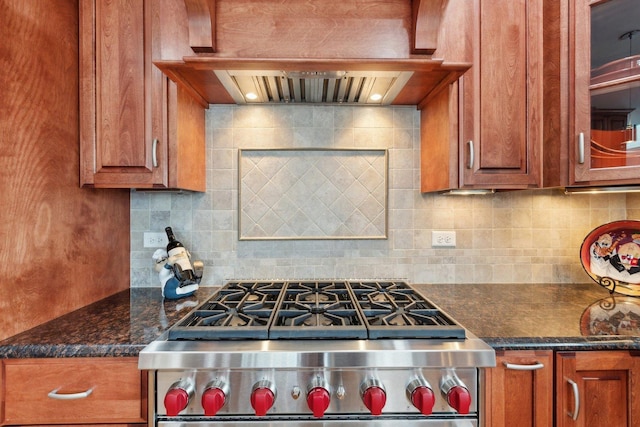 kitchen with tasteful backsplash, stainless steel range, dark stone counters, and custom range hood