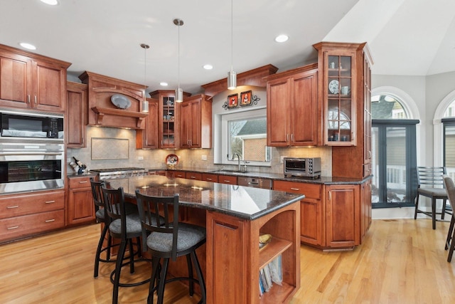 kitchen featuring sink, decorative light fixtures, a center island, dark stone counters, and stainless steel appliances