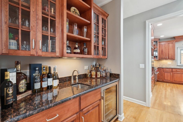 bar with sink, wine cooler, tasteful backsplash, light hardwood / wood-style floors, and dark stone counters