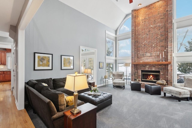 carpeted living room with a healthy amount of sunlight, high vaulted ceiling, and a brick fireplace