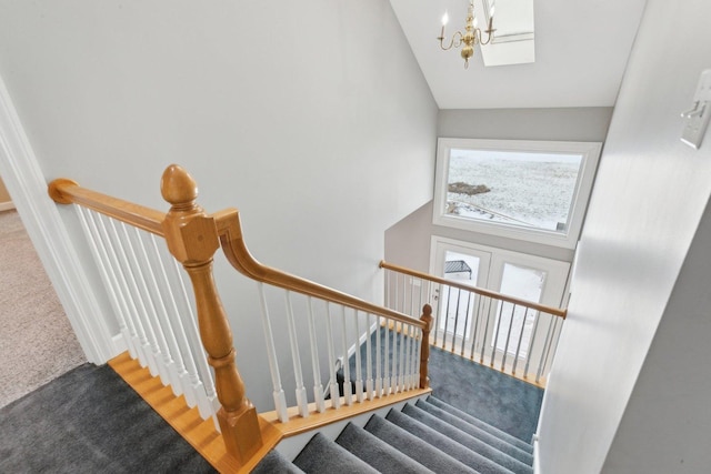 stairway featuring carpet floors, high vaulted ceiling, and a chandelier