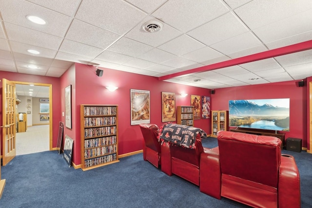 carpeted home theater room featuring a drop ceiling