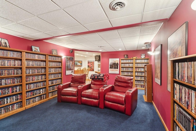 carpeted home theater room with a drop ceiling