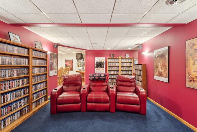 carpeted cinema room featuring a drop ceiling