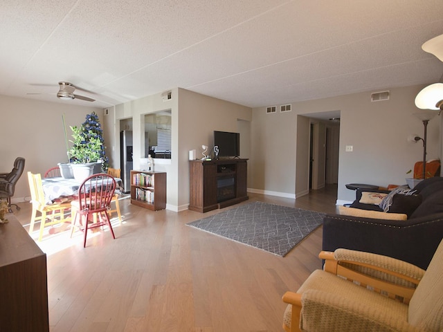 living room with hardwood / wood-style flooring, ceiling fan, and a textured ceiling