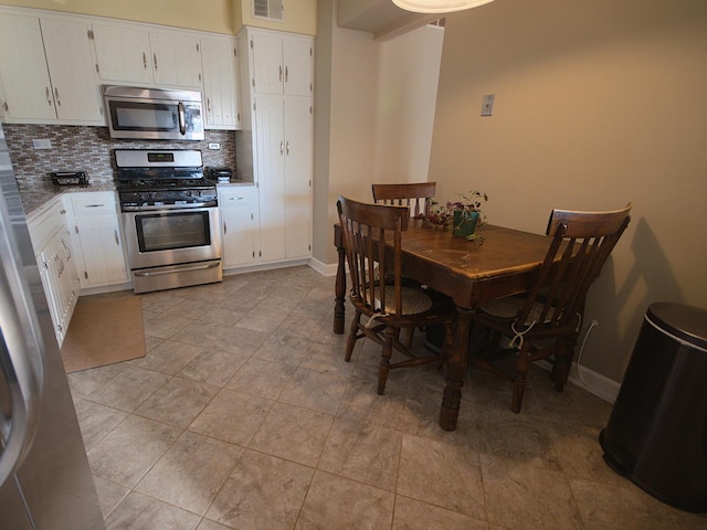 kitchen with tasteful backsplash, light stone counters, white cabinets, and stainless steel appliances