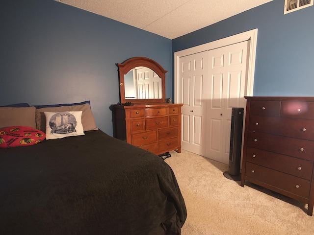 bedroom with light carpet, a textured ceiling, and a closet