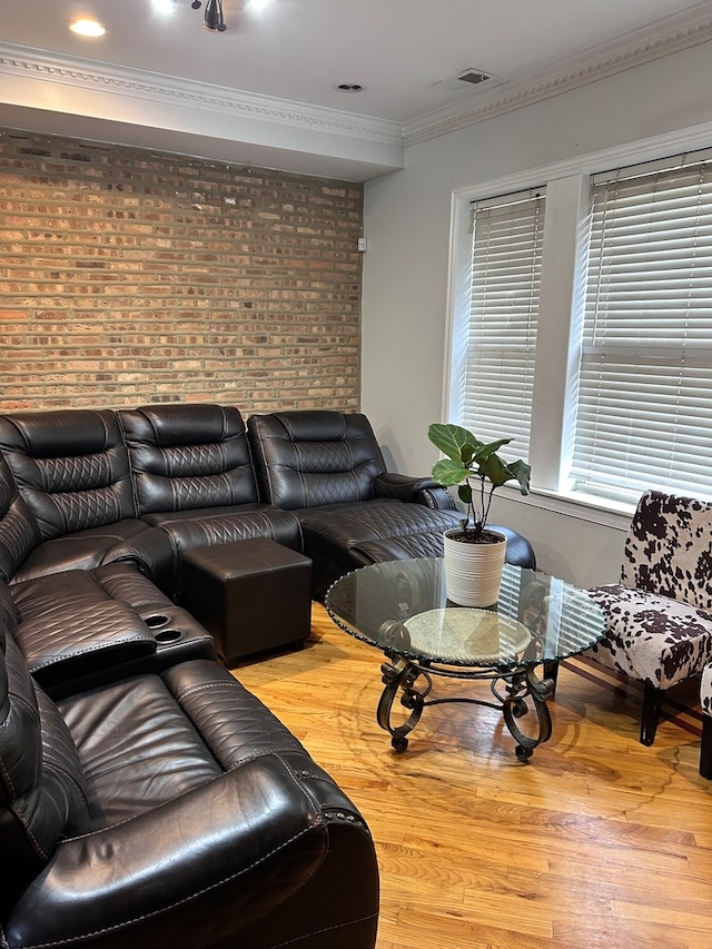 living room with hardwood / wood-style flooring, crown molding, and brick wall