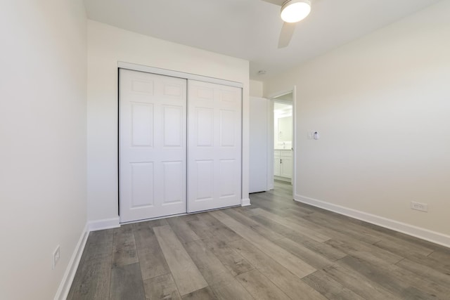 unfurnished bedroom with ceiling fan, a closet, and hardwood / wood-style flooring