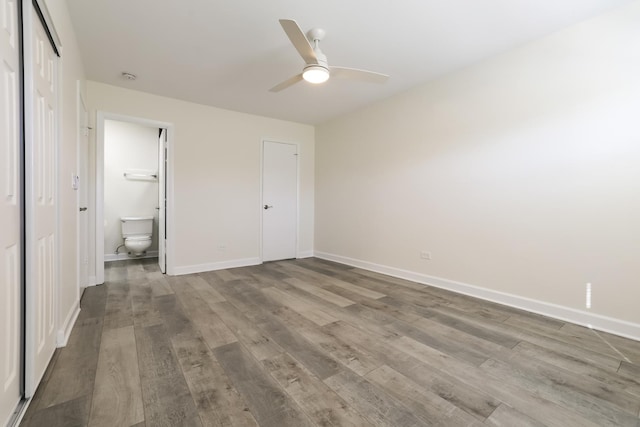 unfurnished bedroom featuring hardwood / wood-style floors, ensuite bathroom, and ceiling fan