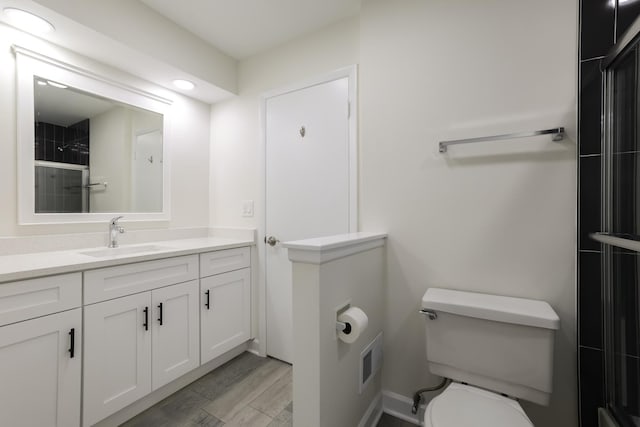 bathroom featuring hardwood / wood-style floors, vanity, toilet, and walk in shower