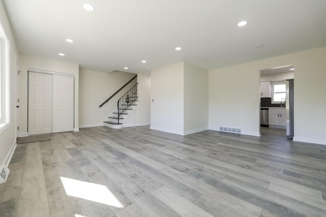 unfurnished living room with light wood-type flooring and sink