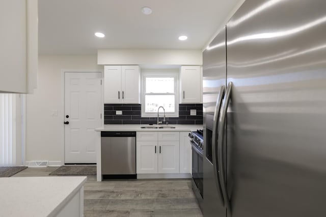 kitchen with white cabinets, sink, appliances with stainless steel finishes, and light hardwood / wood-style flooring