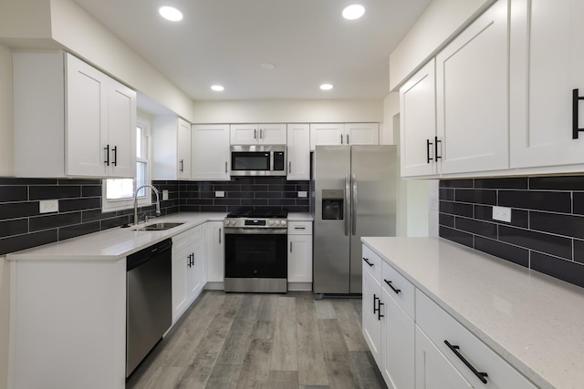 kitchen featuring white cabinets, light wood-type flooring, stainless steel appliances, and sink