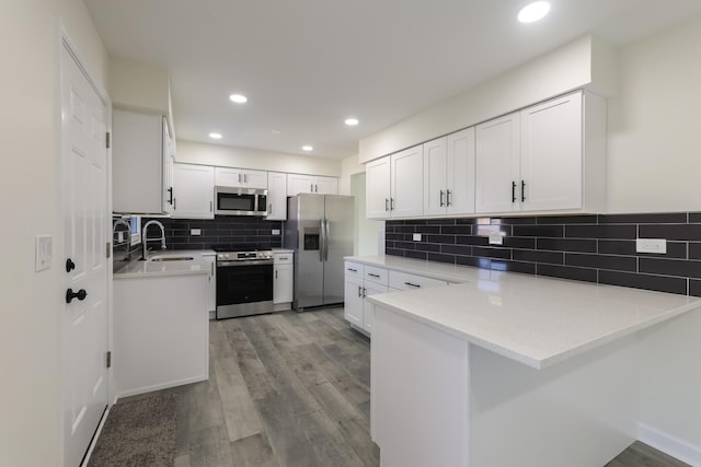 kitchen featuring backsplash, white cabinets, light hardwood / wood-style flooring, appliances with stainless steel finishes, and kitchen peninsula