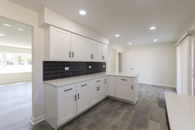 kitchen featuring white cabinets, backsplash, kitchen peninsula, and dark wood-type flooring