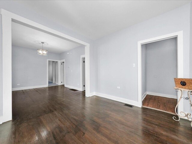 unfurnished living room featuring dark hardwood / wood-style floors and an inviting chandelier