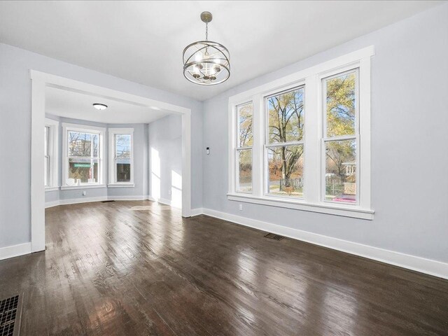 unfurnished dining area with dark hardwood / wood-style flooring, an inviting chandelier, and a healthy amount of sunlight