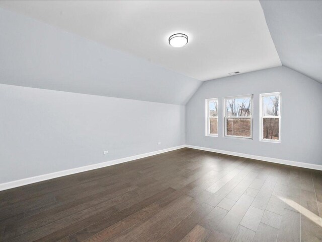 bonus room with dark wood-type flooring and vaulted ceiling