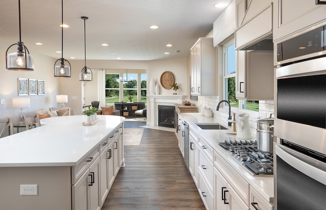 kitchen featuring dark hardwood / wood-style flooring, sink, decorative light fixtures, white cabinets, and a kitchen island