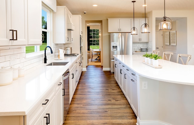 kitchen with backsplash, sink, white cabinets, and pendant lighting