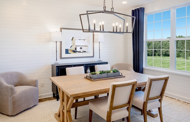 dining area with an inviting chandelier, a wealth of natural light, and wooden walls