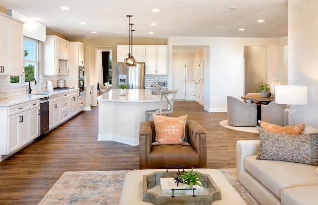 kitchen with backsplash, stainless steel appliances, dark wood-type flooring, a kitchen island, and hanging light fixtures