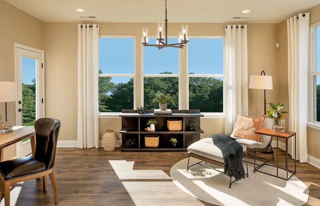 living area featuring a wealth of natural light, wood-type flooring, and a notable chandelier