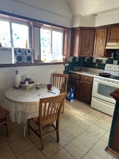 kitchen with light tile patterned flooring, electric stove, backsplash, and vaulted ceiling