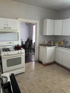 kitchen with gas range gas stove, sink, white cabinets, and extractor fan