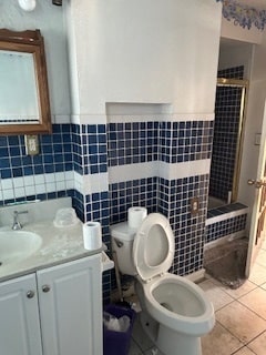 bathroom with tile patterned floors, vanity, toilet, and tile walls