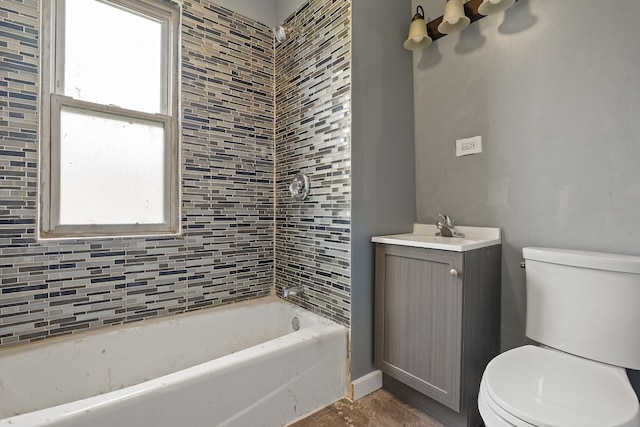 full bathroom with tiled shower / bath, vanity, a healthy amount of sunlight, and toilet