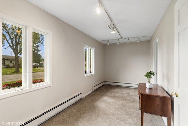 empty room with a baseboard radiator, light carpet, and track lighting